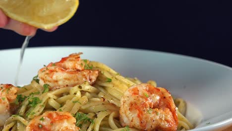 squeezing a fresh lemon over a shrimp and pasta dish