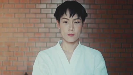 person in bathrobe in front of brick wall
