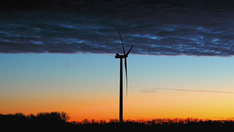 silhouette wind power generator with dramatic, vibrant sunset sky background