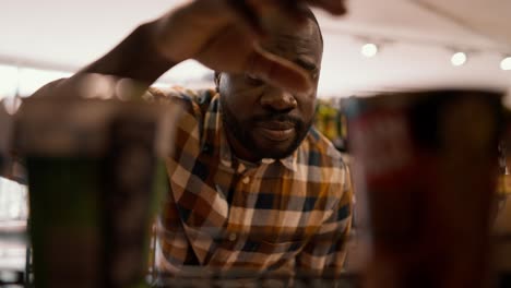 Close-up shot of a Black man choosing one of two items on the floor in a supermarket. The choice of goods in the store, consumer&#039;s view