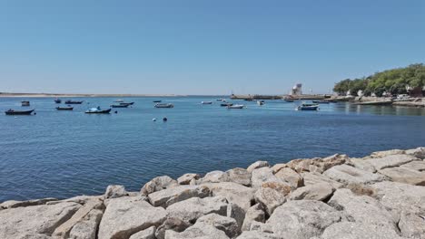 small fishing boats floating in a calm blue sea with a rocky shore in porto on a sunny day