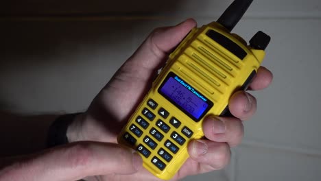 inserindo uma frequência em um rádio amador portátil amarelo, transmitindo e recebendo contra um fundo vermelho piscante