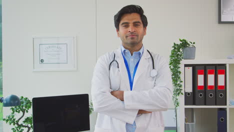 portrait of smiling male doctor or gp with stethoscope wearing white coat standing in office