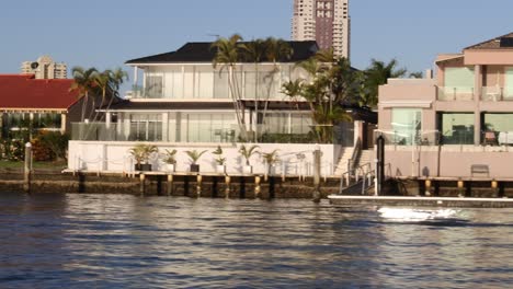 a boat travels past luxurious waterfront homes