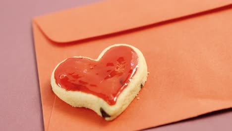 Tarjeta-Del-Día-De-La-Madre-Feliz,-Galleta-Con-Forma-De-Corazón-En-Sobre-Rojo-Contra-Fondo-Rosa