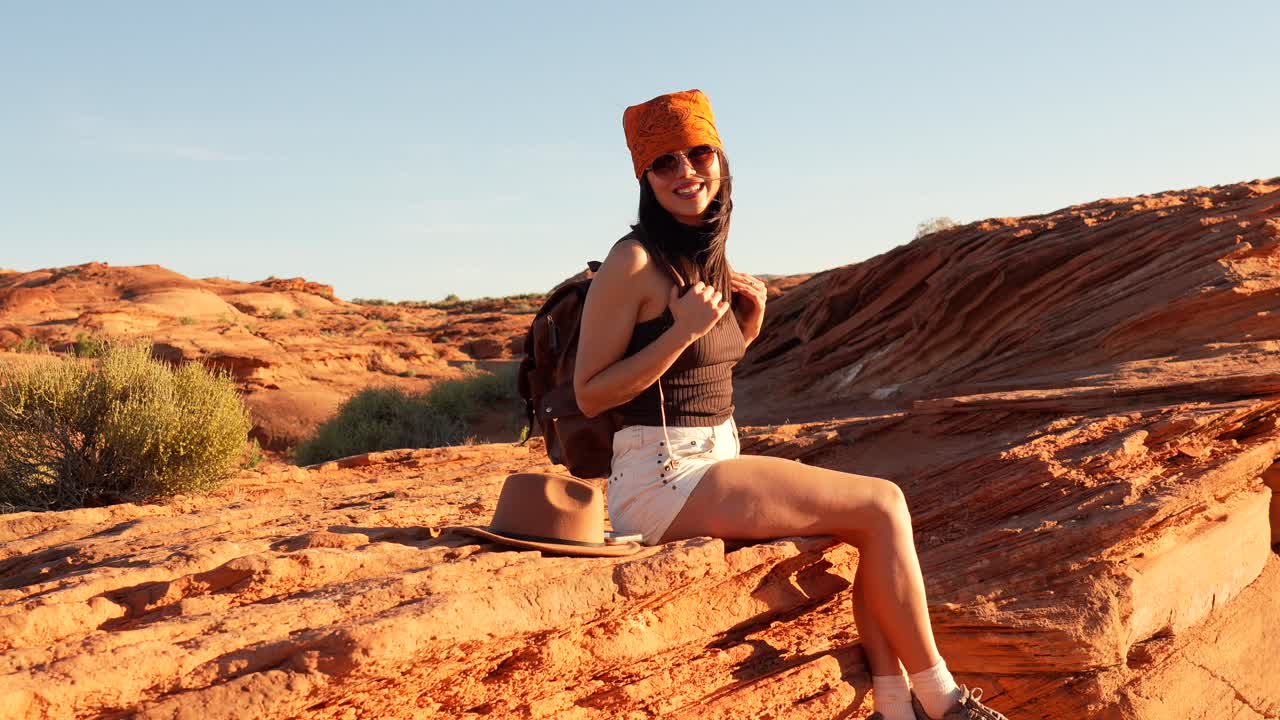 Giovane donna felice seduta su rocce rosse in un paesaggio desertico