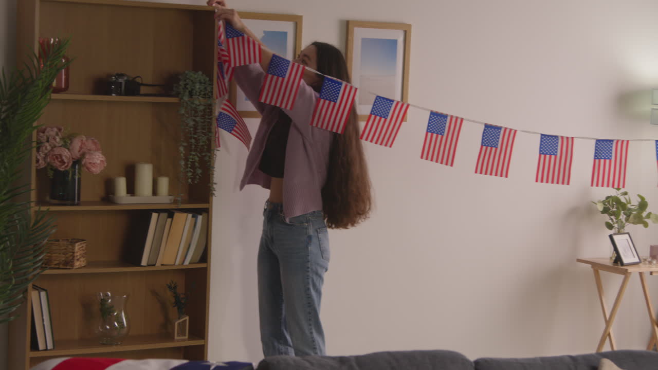 mujer en casa colgando estrellas americanas y rayas bandera bunting para la fiesta celebrando el 4 de julio día de la independencia 1