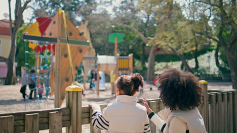 woman looking playground daughter in sunny park close up. family weekend