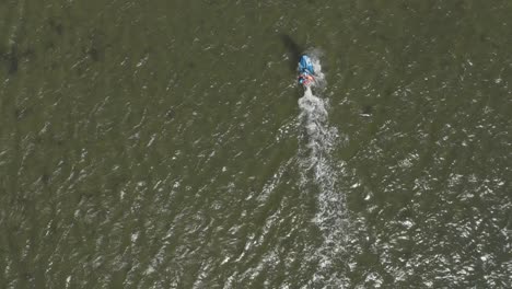 Drone---Aerial-shot-of-a-surfer-on-a-blue,-wavy-and-windy-sea-on-a-sunny-day,-25p