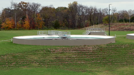 clarifier pools at a wastewater treatment plant slowly rotate and settle, captured in a smooth left-to-right pan, revealing the industrial water treatment process