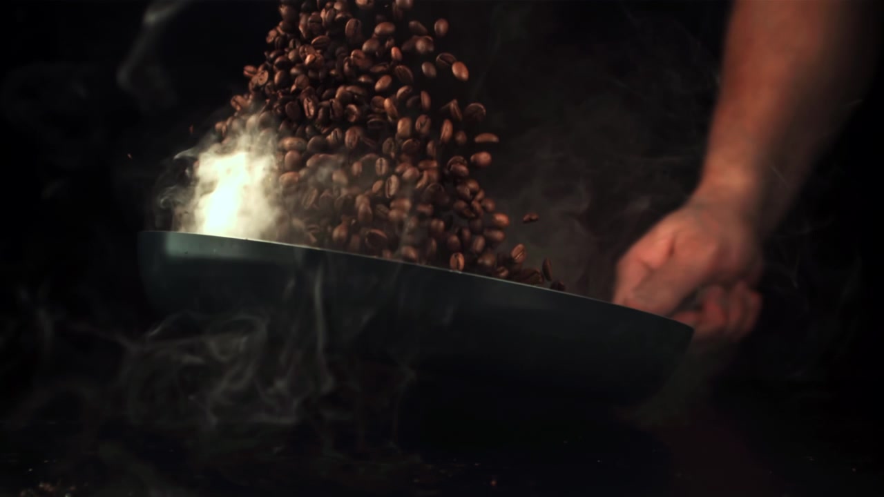 Slow Motion of Coffee Beans Pouring into a Hot Roasting Pan with Smoke