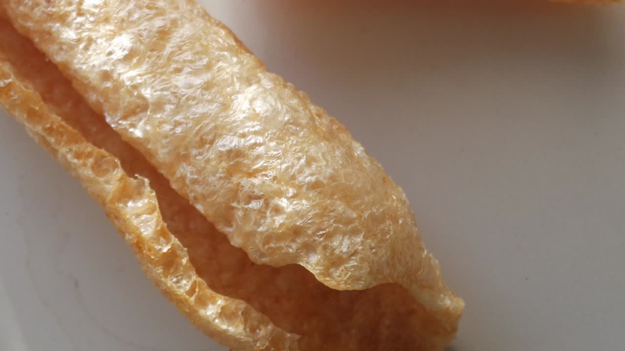 Crunchy, golden pork rind with a crispy texture on a neutral background