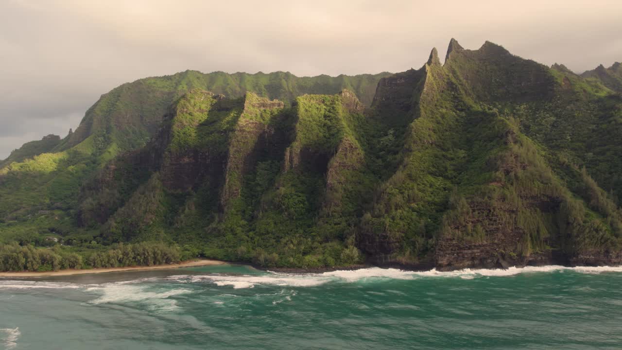 Beautiful nature drone view of green jungle mountain peaks revealing tropical beach on Na Pali park 4K