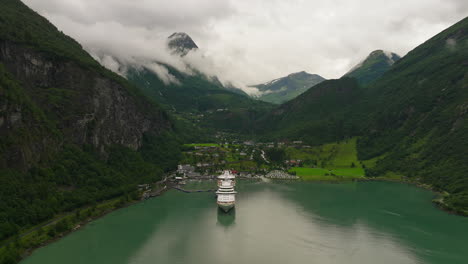 cruise ship docked at tourist town of geiranger, scenic fjord