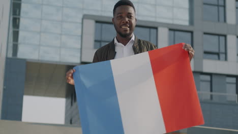 man holding french flag in front of modern building
