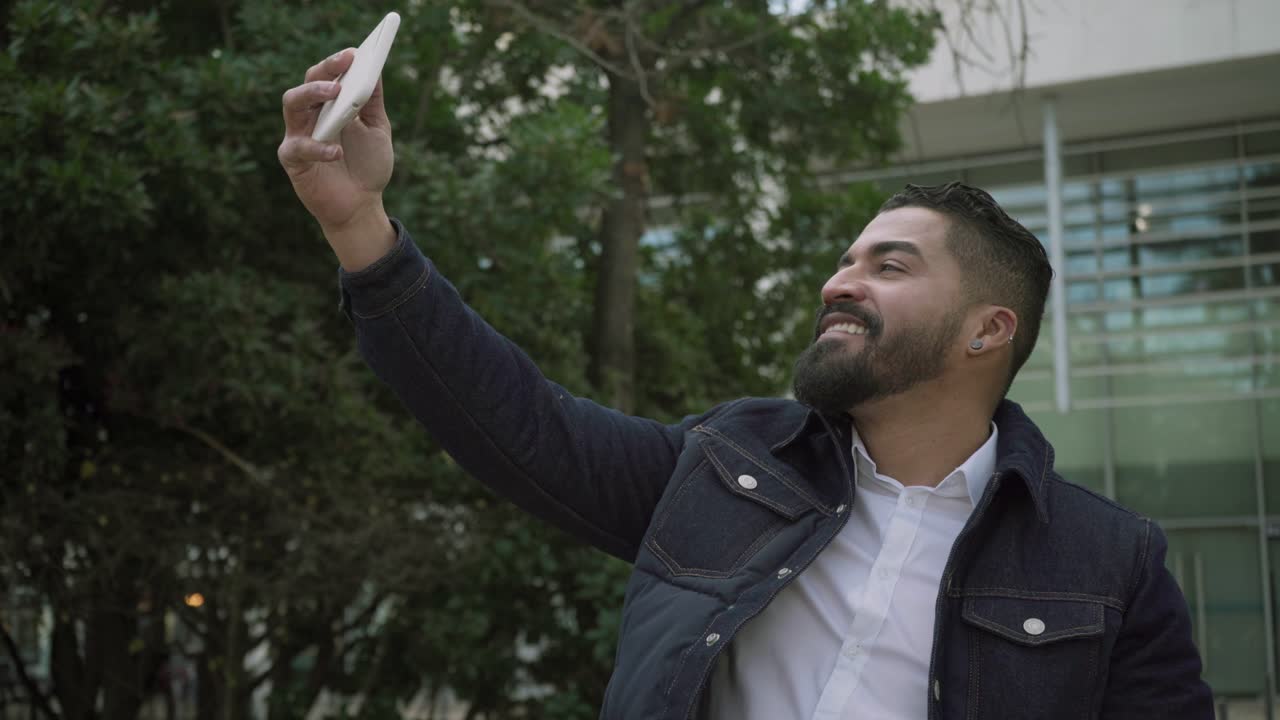 Homem alegre fazendo videochamada na rua