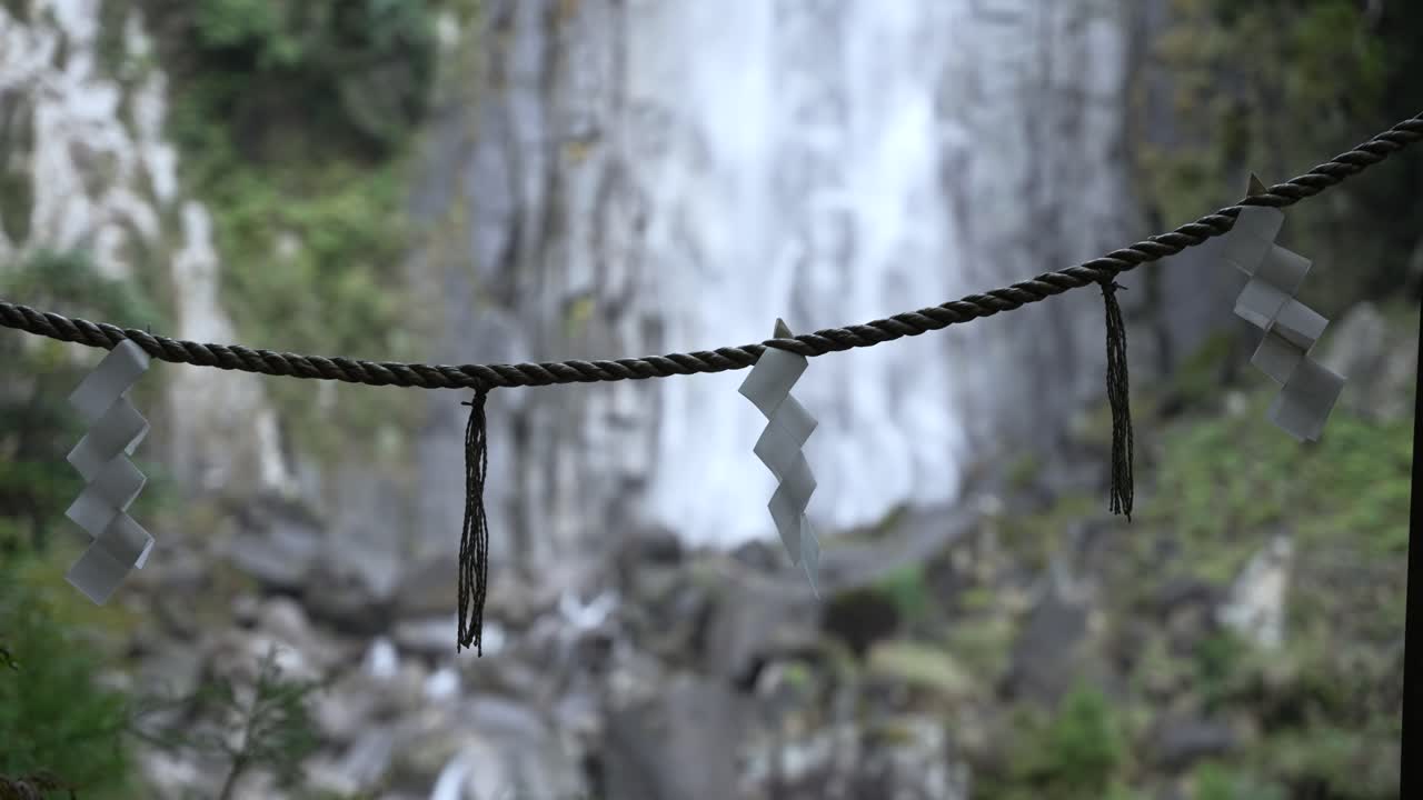 Close up of shide papers hanging on rope in front of Nachi Falls in Nachikatsuura, Japan