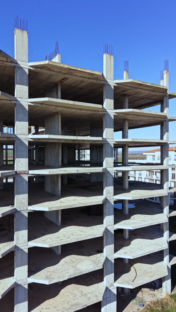 Il cantiere edile mostra una struttura scheletrica sotto un cielo azzurro in un'area urbana durante il giorno