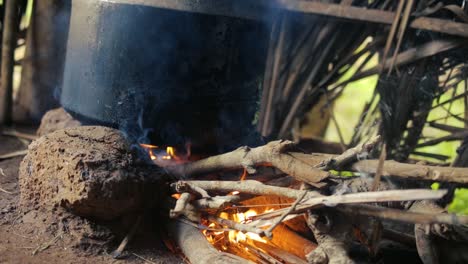 close up low pov shot of pot over campfire in hut, cooking in indian style