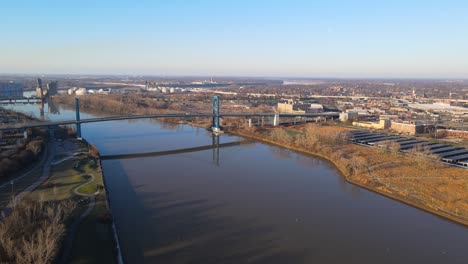 aerial view of a large bridge spanning a wide river with a city in the background