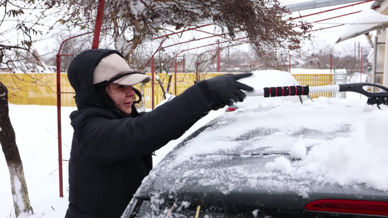 mujer limpiando su auto cubierto de nieve en invierno - cerrar