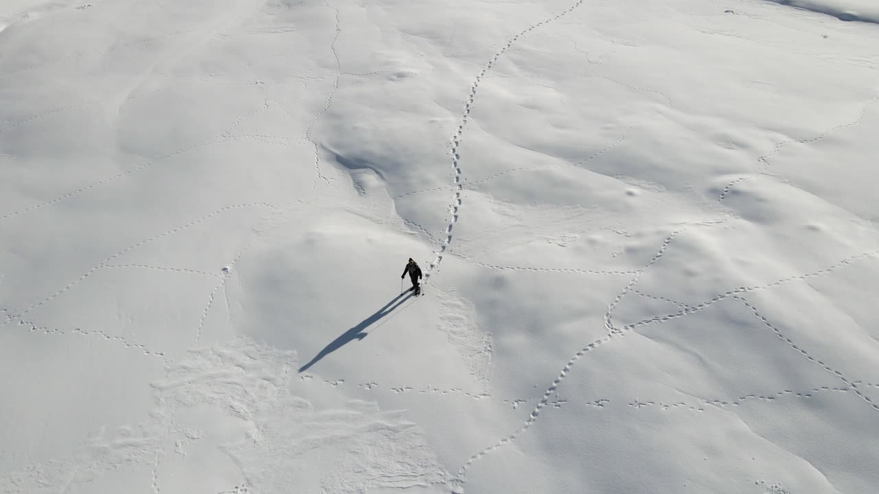 un hombre soltero está caminando en medio de las nevadas montañas italianas con sus raquetas de nieve