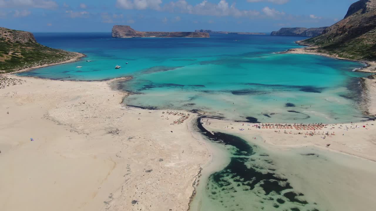 Bluewater Balos beach in Crete Greece with bathing tourists near the shore, Aerial high dolly in shot