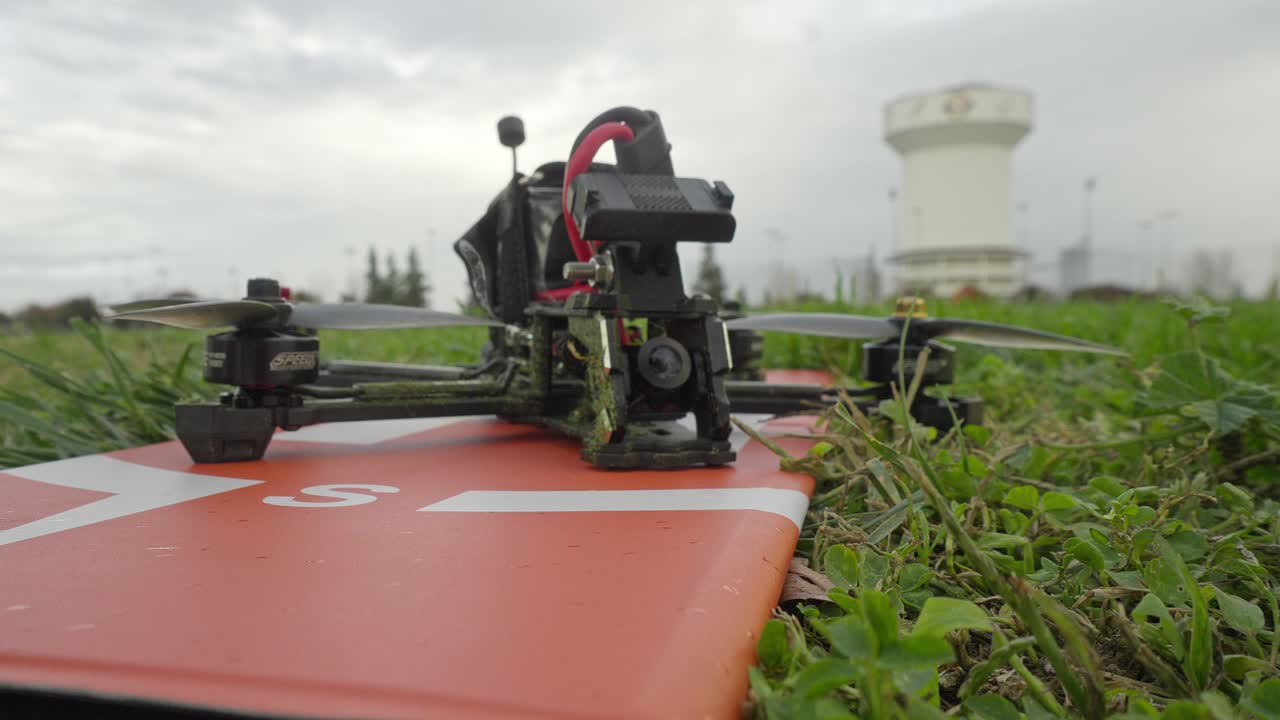 A simple flick of the transmitter switches the FPV drone into arm mode, the camera capturing its quiet readiness on the field