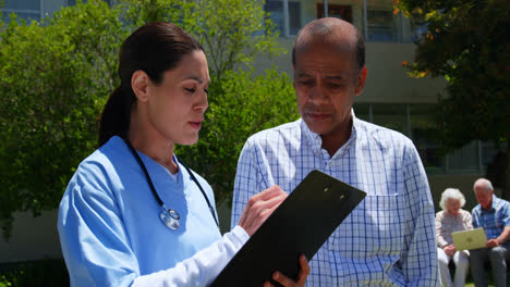 front view of active asian senior man and female doctor discussing over medical report in the garden