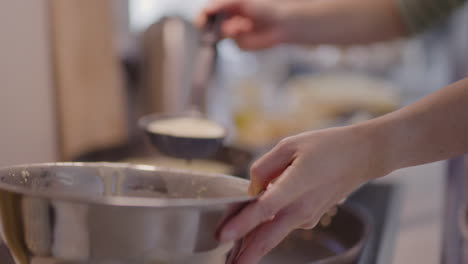 pouring pancake batter into pan while frying