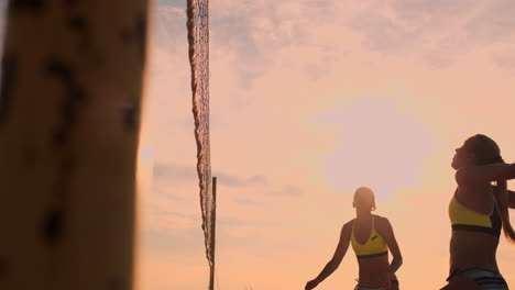 movimiento lento ángulo bajo cerca de la llamarada del sol: chica atlética jugando voleibol de playa salta en el aire y golpea la pelota sobre la red en una hermosa noche de verano. mujer caucásica anota un punto.