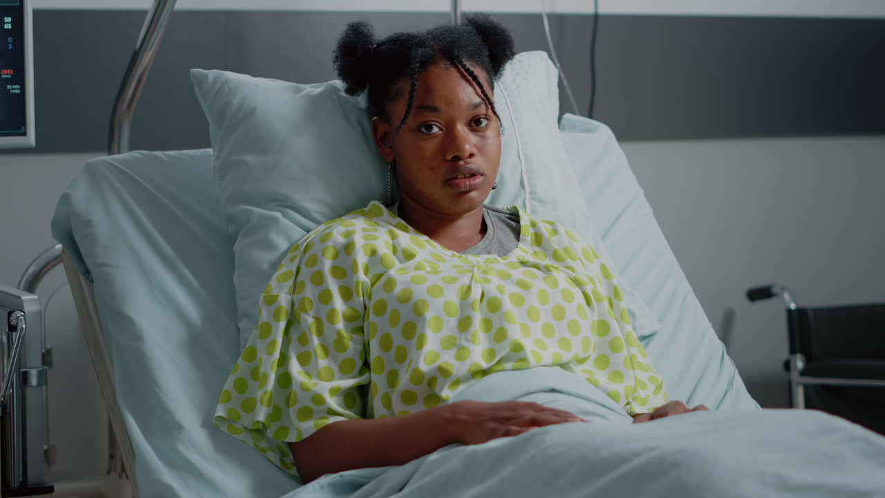 Portrait of woman with IV drip bag in hospital ward bed