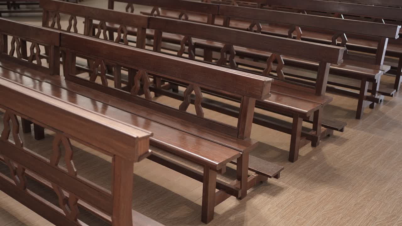 File di panche di legno vuote allineate all'interno di un tranquillo interno di una chiesa