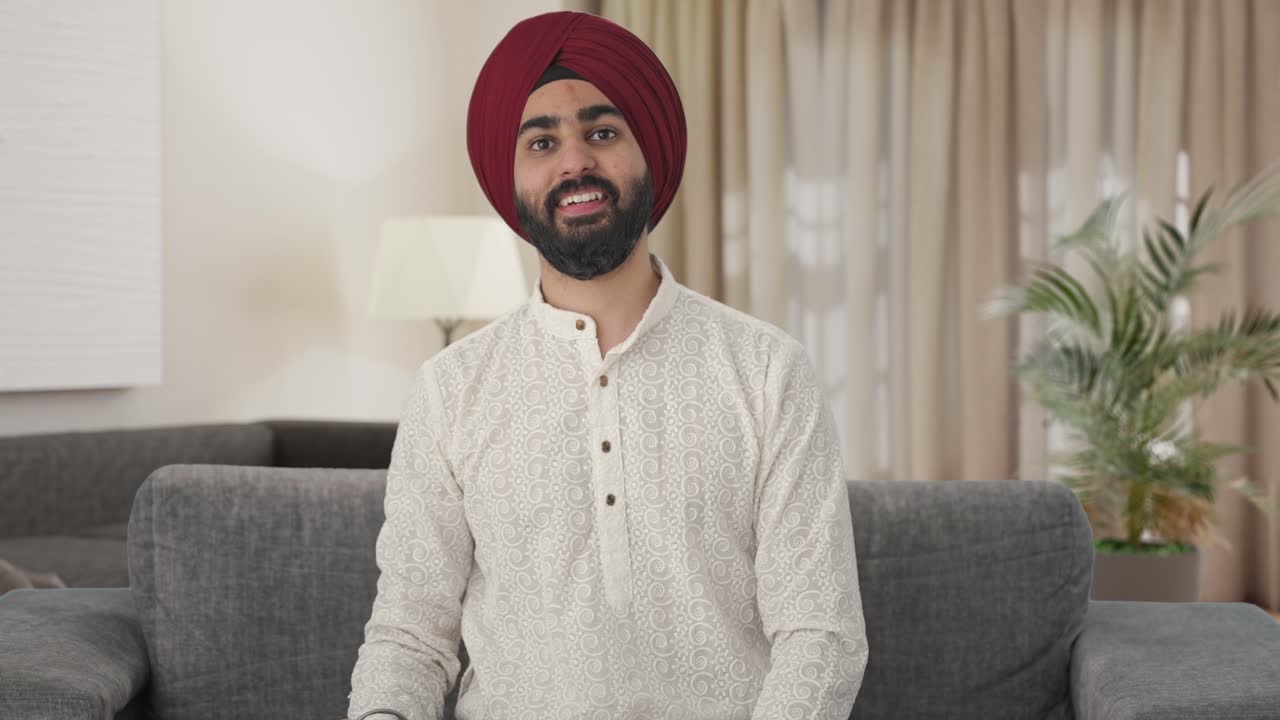 Uomo indiano Sikh felice che guarda la TV