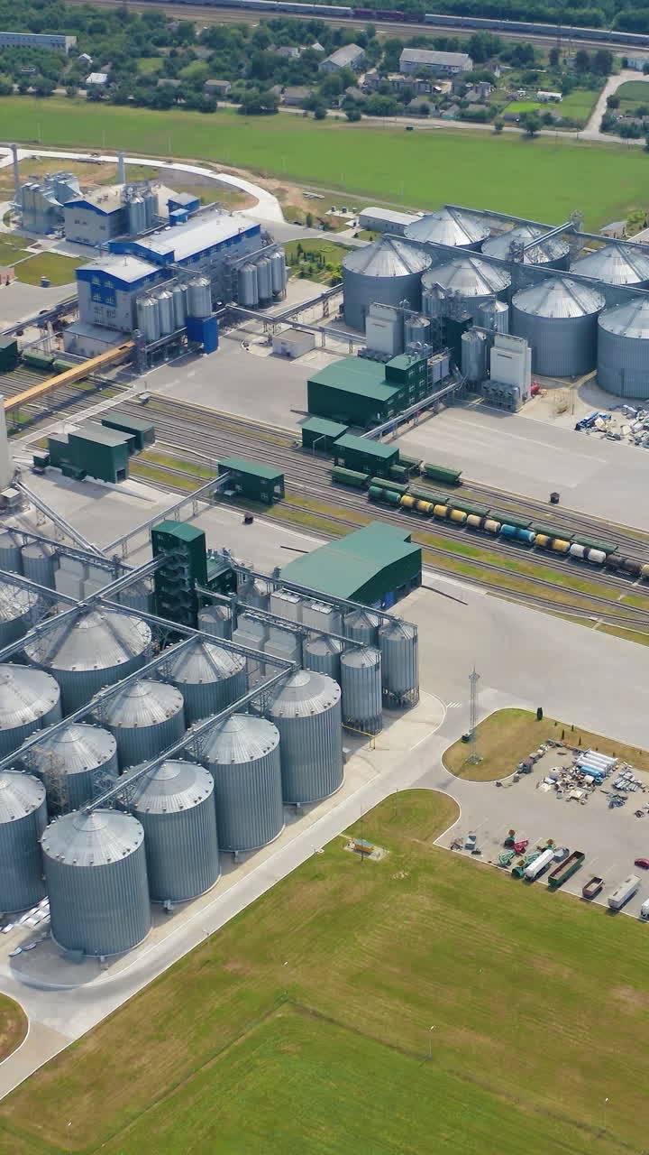 Modern industrial grain elevator storages. Aerial view of big factory metal storages. Vertical video
