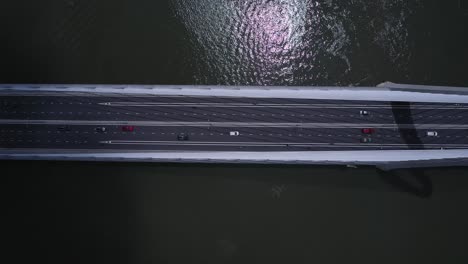 top down view of suspension bridge over river with road traffic in strong contrasty light