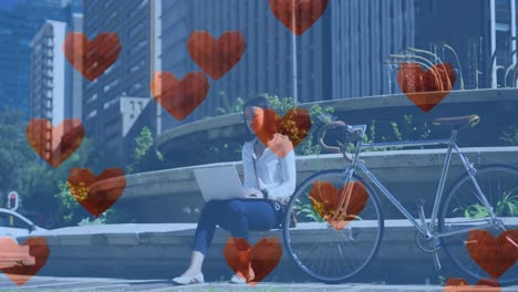 Animación-De-íconos-De-Amor-De-Corazón-Sobre-Una-Mujer-Usando-Una-Computadora-Portátil-En-La-Ciudad