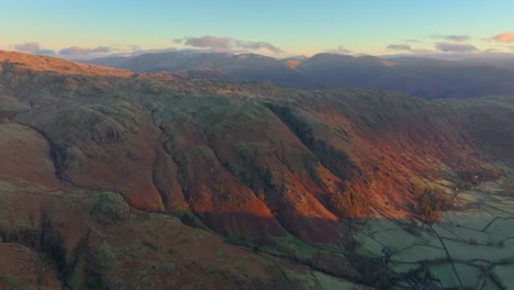 winter dawn light striking crags and distant mountaintops. langdales, english lake district, cumbria, uk.