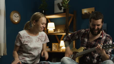 couple singing and playing guitar in bedroom