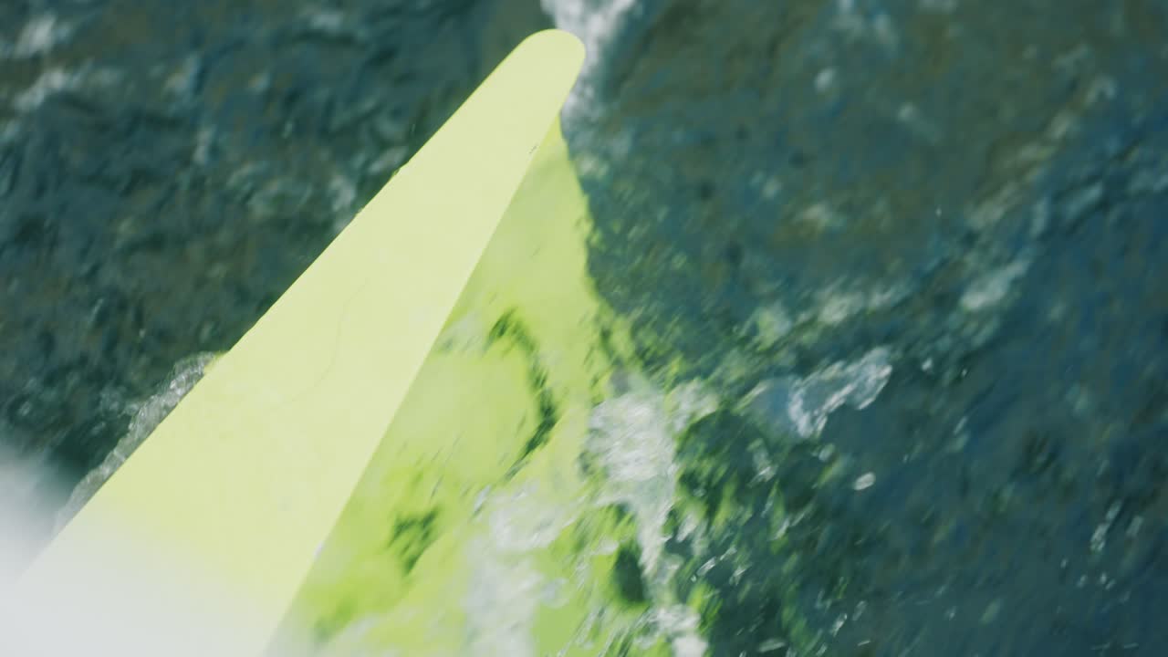Close-up of a yellow daggerboard slicing through dark sea water, seen from a Class 40 racing sailboat
