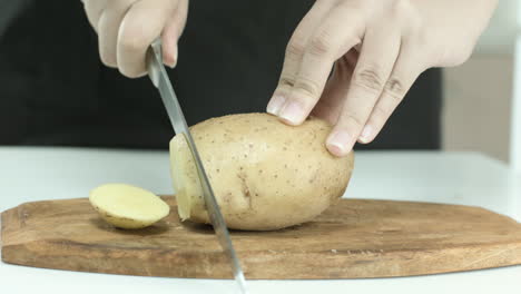 mujer cortando papas en una tabla de cortar