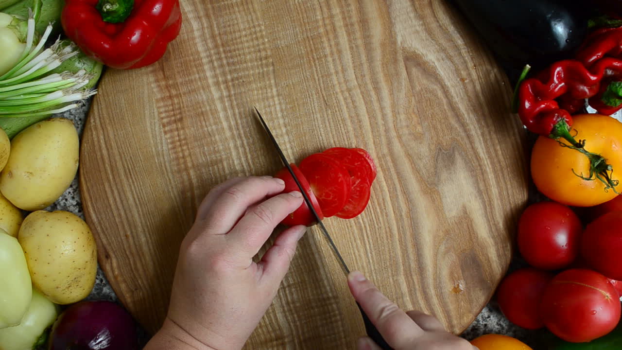 The cook cuts tomato. Preparation of vegetables