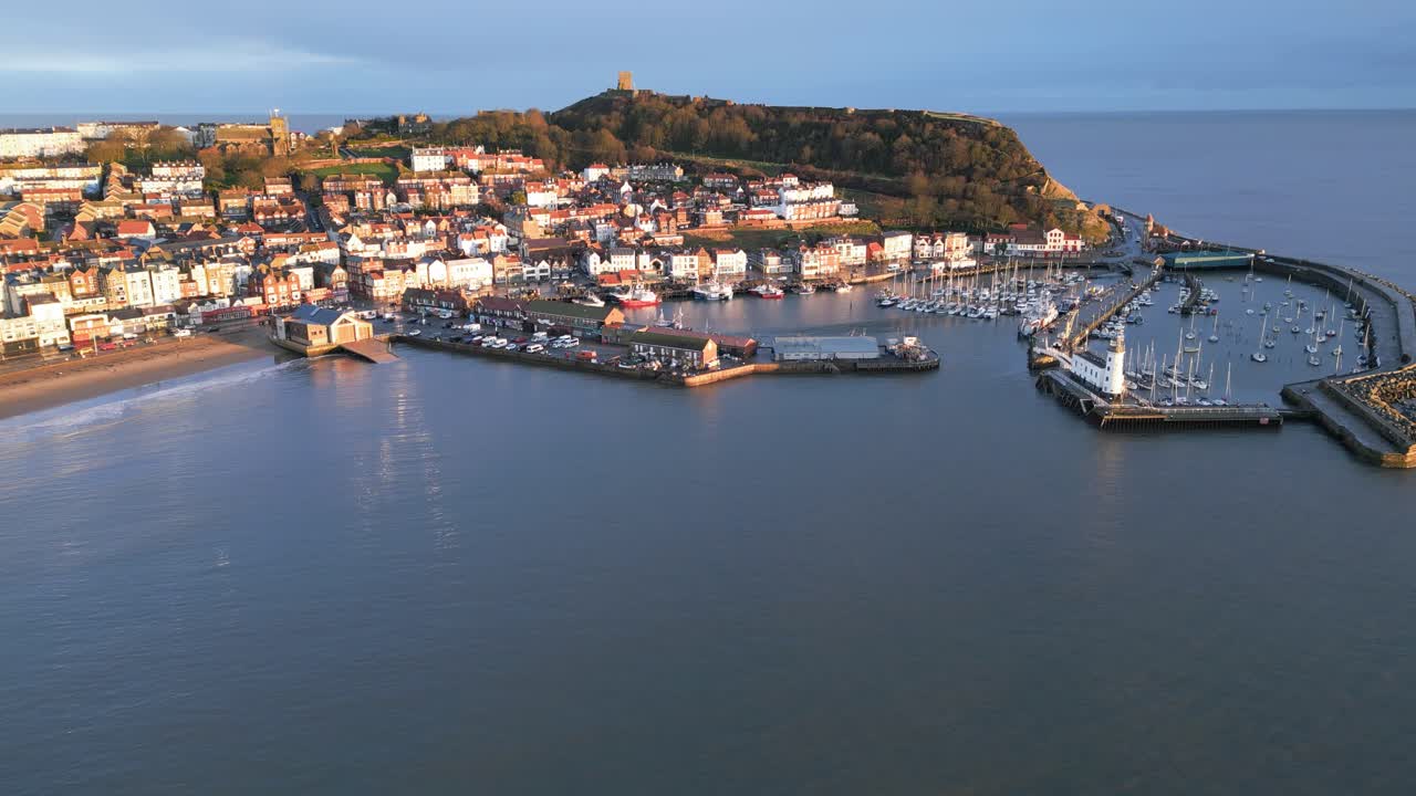 Ripresa drone di una città con una collina e un porto con barche durante il giorno a Scarborough, North Yorkshire, Inghilterra.