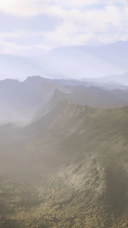 Vast landscape with misty mountains under a soft sky at dawn