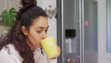 Thoughtful-woman-looking-away-while-having-coffee-in-the-kitchen-4K-4k