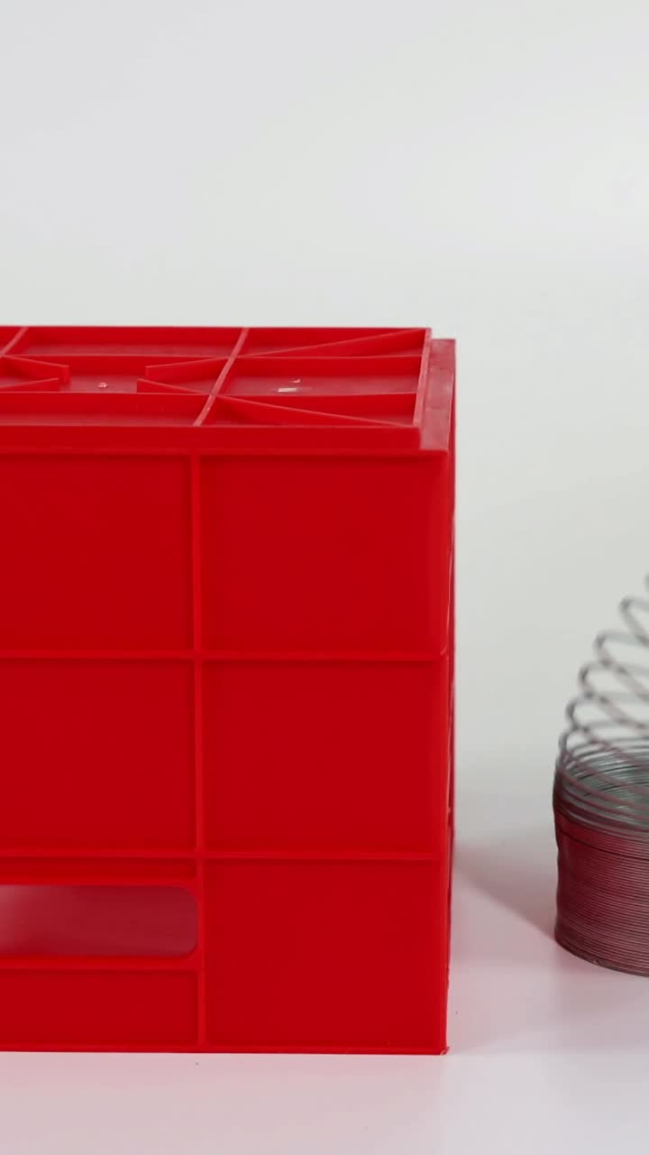 손은 빨간 블록 위에서 슬링키를 펼치고 있습니다.