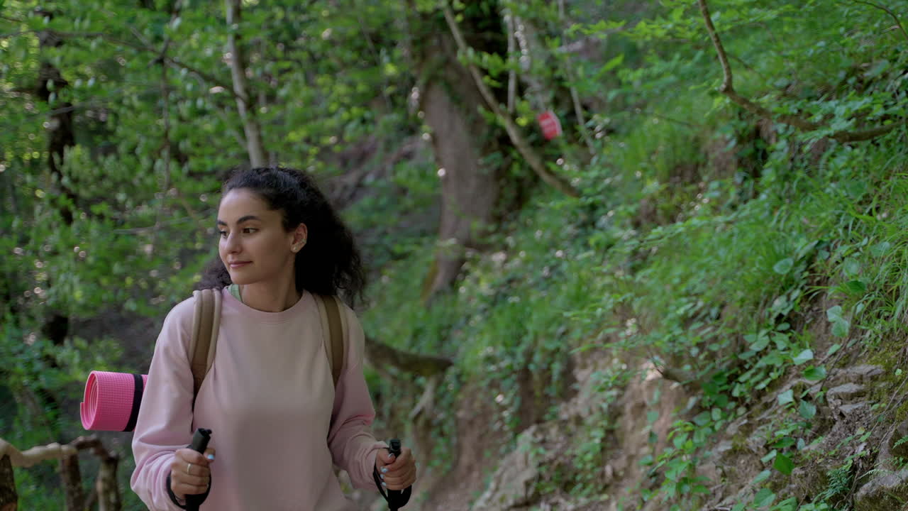 mujer caminando en el bosque con palos de senderismo