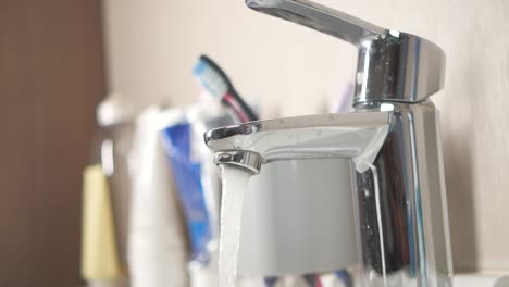 close up of a chrome faucet running water in a bathroom sink