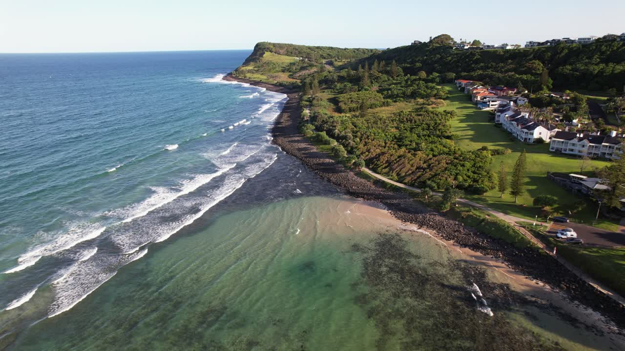 Lennox Point Headland With Vegetation And Waves Splashing. Lennox Head, NSW, Australia. aerial pullback shot