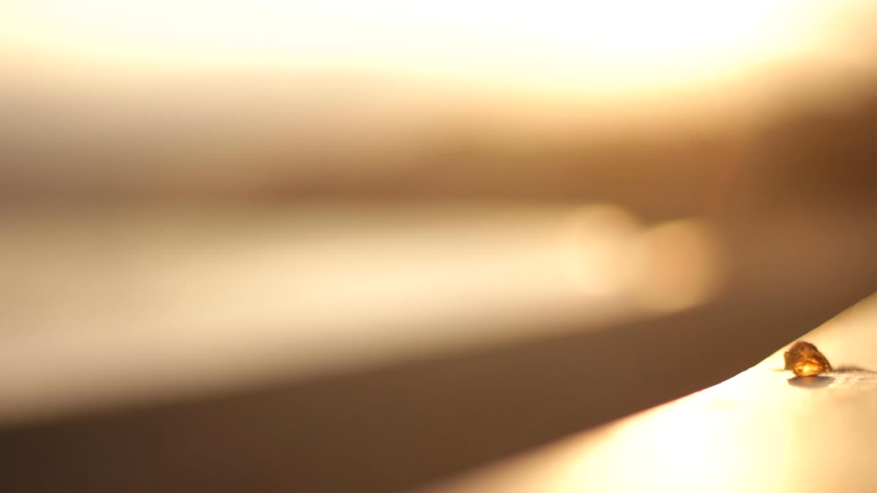 CRYSTAL OF CITRINE PLACED IN THE FORGROUND OF A SUNSET BY THE OCEAN